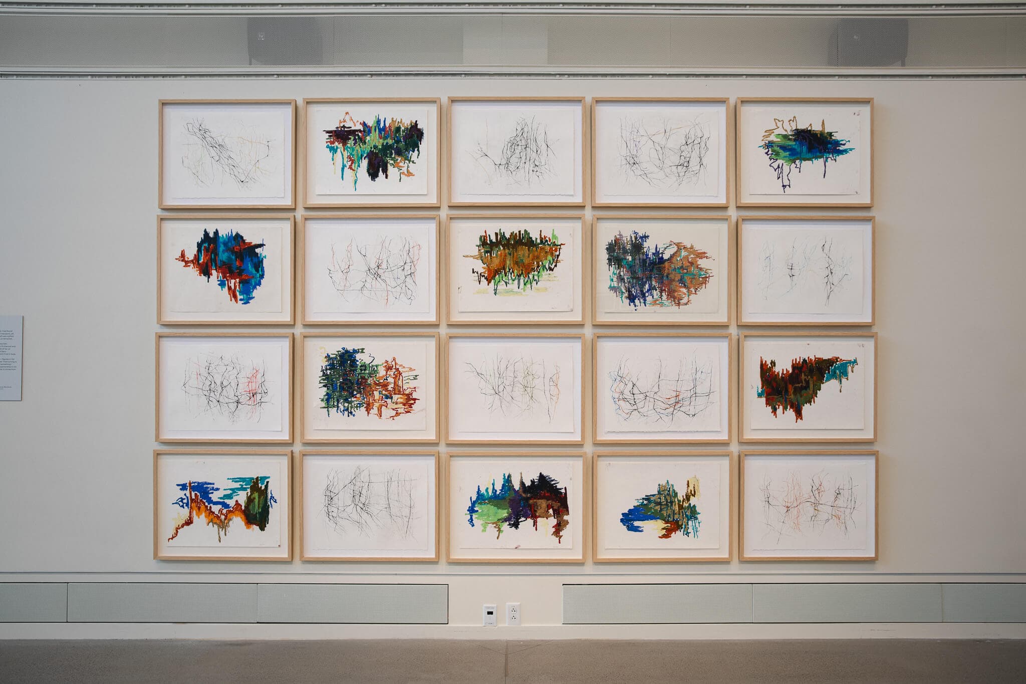 Framed drawings form a grid on a gallery wall.