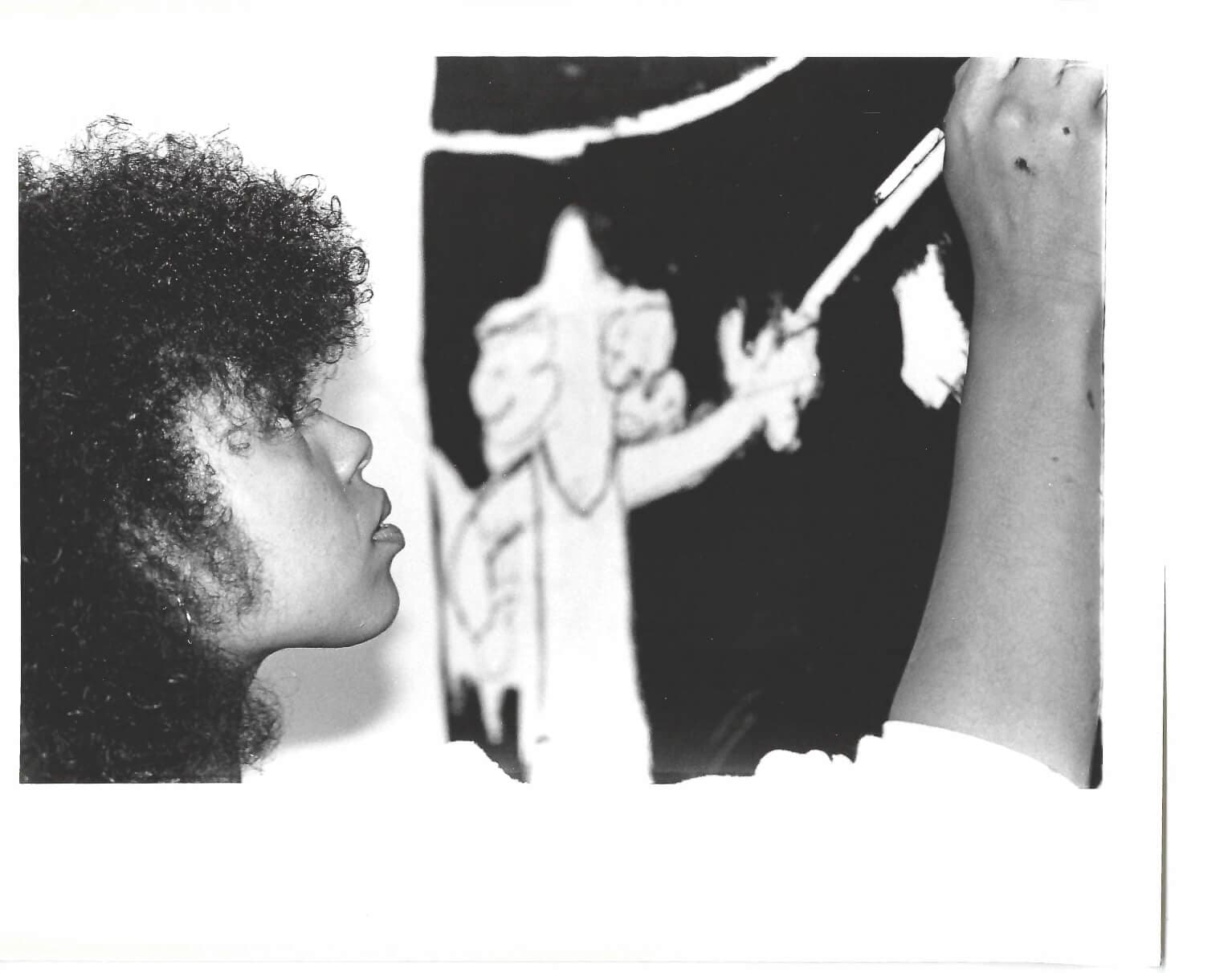 A young girl works on a wall mural.